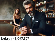 Респектабельный мужчина средних лет в классическом костюме сидит в пабе за бокалом превосходного виски. На заднем плане видна очаровательная молодая девушка. Стоковое AI-изображение, AI-художник Сергей Сергеев / Фотобанк Лори