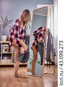 Large full length standing mirror and female changes pants near it. Стоковое фото, фотограф Владимир Григорьев / Фотобанк Лори