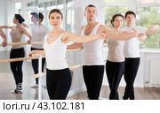 Pretty young girl in black and white sportswear, participating 2nd position of ballet stance at barre with group in choreography studio. Стоковое фото, фотограф Яков Филимонов / Фотобанк Лори