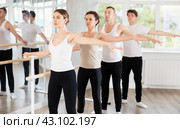 Pretty young girl in black and white sportswear, participating 2nd position of ballet stance at barre with group in choreography studio. Стоковое фото, фотограф Яков Филимонов / Фотобанк Лори