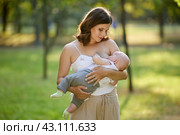 Breastfeeding on public by mother with little boy in park. Стоковое фото, фотограф Владимир Григорьев / Фотобанк Лори