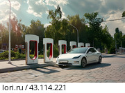 Припаркованный электромобиль под заряжается на электрической зарядной станции. Стоковое AI-изображение, AI-художник Максим Коломыченко / Фотобанк Лори