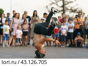 Moscow, Russia- August 14, 2022: Street life in summer day. Big audience has fun. Breaking, also called breakdancing, b-boying or b-girling, is athletic style of street dance. Man stands on his head. Редакционное фото, фотограф YuryKara / Фотобанк Лори