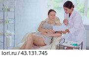 Woman doctor give patient medical documents for review before carrying out cosmetic procedure. Стоковое видео, видеограф Яков Филимонов / Фотобанк Лори