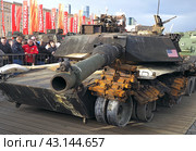Люди смотрят на дуло вниз у американского танк Abrams М1А1. Выставка трофейного вооружения и военной техники, захваченной российскими военными в ходе спецоперации. Парк Победы на Поклонной горе, Москва (2024 год). Редакционное фото, фотограф SevenOne / Фотобанк Лори