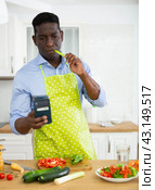 Man using smartphone while preparing food at home. Стоковое фото, фотограф Татьяна Яцевич / Фотобанк Лори