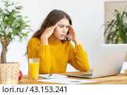 Woman massaging temples of head due to headache from long work. Стоковое фото, фотограф Natalia Gdovskaia / Фотобанк Лори