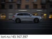 Автомобиль Volkswagen Touareg Third generation (CR) мчится по вечерней дороге. Белый кроссовер едет по ночной улице. Соблюдение скоростного режима на дорогах (2021 год). Редакционное фото, фотограф Константин Григорьев / Фотобанк Лори