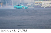 A blue drift car passes a large circle with smoke from under the wheels at the Mega Belaya Dacha site. The drift festival. Russia. Moscow. 19.05.2024. Редакционное видео, видеограф Ярославский Максим / Фотобанк Лори
