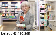 Interested old female client scanning QR of medical product held in hand in chemist's shop. Стоковое видео, видеограф Яков Филимонов / Фотобанк Лори