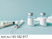 Syringe and glass vial on blue background table. Medical Vials group, needles, ampoules, bottle with medicines or vaccine. Disease treatment. Creative Banner. Anti-aging beauty injections. Vaccination. Стоковое AI-изображение, AI-художник Марина Демидюк / Фотобанк Лори