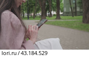 Business woman in the park in the summer writes a message on the phone. Стоковое видео, видеограф Громов Александр / Фотобанк Лори