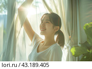 Young asian woman unveil curtain and looking out of window in the morning. Beautiful girl nearly window after waking up fully rested and open curtains. Start the new day with happiness. Relax, resting. Стоковое AI-изображение, AI-художник Марина Демидюк / Фотобанк Лори