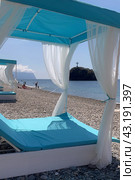 A blue and white beach umbrella with white curtains is set up on a beach. Стоковое фото, фотограф svetograph / Фотобанк Лори