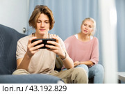 Boy sitting on sofa with phone, mother trying to talk. Стоковое фото, фотограф Яков Филимонов / Фотобанк Лори