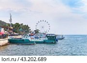 LISTVYANKA VILLAGE, IRKUTSK REGION, RUSSIA - August 03, 2023: Tourists like to relax in village of Listvyanka, take boat trips, dine in cafe overlooking Lake Baikal, and ride on observation wheel. Редакционное фото, фотограф Виктория Катьянова / Фотобанк Лори