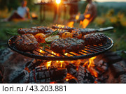 Barbecue moment in nature. Shown in the foreground is a grill cooking succulent cuts of meat and vegetables such as tomatoes and zucchini. The flames under the grill create a bright, warm glow that brings out the texture and deliciousness of your food. Стоковое AI-изображение, AI-художник Анна Кривицкая / Фотобанк Лори