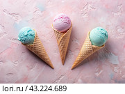 The banner. Sweet dessert. Ice cream cones with different flavors. Blue, pink ice cream on a background of two pastel colors: blue and pink. Стоковое AI-изображение, AI-художник Photojuli / Фотобанк Лори