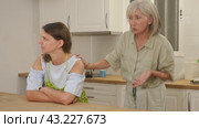 Senior woman scolding her adult daughter cooking breakfast in kitchen. Стоковое видео, видеограф Яков Филимонов / Фотобанк Лори