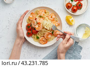 Pasta bavette with fried shrimps, bechamel sauce. Woman hands in frame, girl eats pasta, top view. Стоковое фото, фотограф Natalia Gdovskaia / Фотобанк Лори