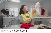 An inspired seamstress is experimenting with fabric in her creative workshop, using a mannequin as a model. Стоковое видео, видеограф Strunov David / Фотобанк Лори