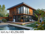 Modern two-story house with wooden trim, large windows and a spacious terrace. The house is equipped with an external air conditioning unit installed on the ground floor. Next to the house there is a swimming pool with clean water and a neatly decorated surrounding area with green lawns and garden furniture. The area is fenced with a wooden fence, creating a cozy and private space. Trees and shrubs grow around the house, adding natural surroundings and greenery. Стоковое AI-изображение, AI-художник Анна Кривицкая / Фотобанк Лори