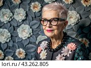 Portrait of a stylish, fashionable elderly woman, a pensioner of 70 years old, wearing glasses and clothes with floral prints. The concept of the elderly. Стоковое AI-изображение, AI-художник Photojuli / Фотобанк Лори