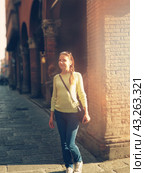 Happy woman portrait walking on the old Bologna street. Smiling girl in yellow sweater walking to the University in morning sun lights. Teenager portrait outdoors. Стоковое фото, фотограф Константин Григорьев / Фотобанк Лори