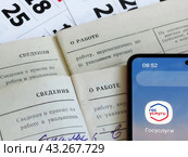 Пенсионные накопления. Страницы трудовых книжек на фоне календаря и электронное приложение Государственные услуги. Пора на пенсию. (2024 год). Редакционное фото, фотограф Татьяна Т / Фотобанк Лори