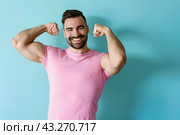 A photo of a strong dark-haired guy showing off his biceps, wearing a purple T-shirt highlighted on a light blue background. Стоковое AI-изображение, AI-художник Ярославский Максим / Фотобанк Лори