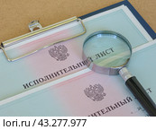 Поиск должника. Лупа лежит на исполнительных листах на принудительное удержание задолженности. Стоковое фото, фотограф Татьяна Т / Фотобанк Лори