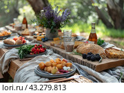 Table set for an outdoor picnic. There are a variety of dishes and drinks on the table: fresh fruits, berries, fresh bread, cheese, herbs and bottles of drinks. The composition is complemented by a vase with wildflowers, which gives the table additional charm. The table is covered with natural fabrics, creating an atmosphere of comfort and natural harmony. This photo is ideal for illustrating picnics, family meals outdoors, farm products and a healthy lifestyle. Стоковое AI-изображение, AI-художник Анна Кривицкая / Фотобанк Лори