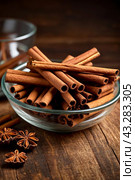 Ceylon cinnamon sticks in glass plate on wooden board, rustic style. Still life natural food of sri lankan cinnamon sticks on table at grey wall. Delicious tasty healthy concept. Copy ad text space. Стоковое AI-изображение, AI-художник Aleksandr Golubev / Фотобанк Лори