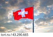 Flag of Switzerland flying in the wind against a cloudy sky. Стоковое фото, фотограф FotograFF / Фотобанк Лори