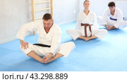 Athletes before training martial arts performs stretching butterfly pose to warm up muscles. Стоковое видео, видеограф Яков Филимонов / Фотобанк Лори