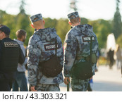 Translation of the text in Russian into English - Police. Police patrol in the public city park of Moscow. Guardsmen. Sunny summer day. Safety and security concepts. Backs, rear view. (2022 год). Редакционное фото, фотограф YuryKara / Фотобанк Лори