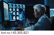 An elderly female doctor looks at the fluorographic images of the brain on the monitor. Стоковое AI-изображение, AI-художник Ярославский Максим / Фотобанк Лори