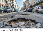 The terrible condition of the roads. A hole in the asphalt on a city street. Road repairs. A city street of poor quality. Стоковое AI-изображение, AI-художник Photojuli / Фотобанк Лори