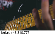 Close-up of a man's fingers with a green plectrum striking the top two strings of an electric guitar. The guitar has a black body. Slow motion of the vibration of the strings. Стоковое видео, видеограф Воловодов Владимир / Фотобанк Лори