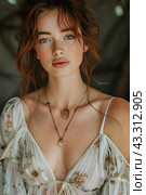 Young girl in boho style indoors with blurred background. She is wearing a lightweight blouse with a floral pattern and a plunging neckline, complete with ties at the chest. Her hair is pulled back into a messy bun with loose strands creating a romantic and natural look. The girl's face is decorated with light makeup, which emphasizes her natural beauty and blue eyes. A thin necklace with a pendant hangs around the girl’s neck. The background of the photo is blurred, which allows you to focus on the model and her outfit. Стоковое AI-изображение, AI-художник Анна Кривицкая / Фотобанк Лори