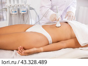 Female patient undergoing ultrasonic cavitation procedure on belly at aesthetic medicine clinic. Стоковое фото, фотограф Яков Филимонов / Фотобанк Лори