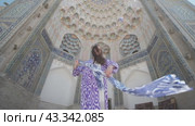 A young woman with long hair in an oriental robe and a skullcap walks through an ancient oriental city. Стоковое видео, видеограф Aleksey Kidisyuk / Фотобанк Лори