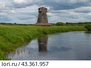 Cтарая деревянная мельница (декорация для съемок исторических фильмов) на берегу реки Сороть облачным июньским днем. Урочище Лосковицы (Лосковское). Псковская область (2024 год). Стоковое фото, фотограф Виктор Карасев / Фотобанк Лори
