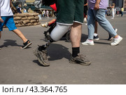 Мужчина с протезом ноги идет по улице в городе Москве, Россия (2024 год). Редакционное фото, фотограф Николай Винокуров / Фотобанк Лори