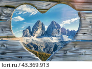 A wooden board with a hole in the shape of a heart with a background from the Alpine mountains. Стоковое AI-изображение, AI-художник Ярославский Максим / Фотобанк Лори