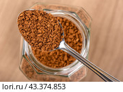Instant granulated coffee in a spoon over a jar on a wooden background. Стоковое фото, фотограф Сергей Долгов / Фотобанк Лори