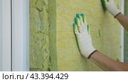 Builder insulates the external walls with mineral sheet insulation in protective gloves. Thermal insulation work, house renovation. Стоковое видео, видеограф Дмитрий Кобзев / Фотобанк Лори