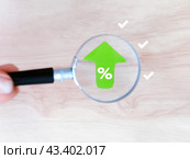 Концепция роста и приумножения. Увеличенная лупой зеленая стрелка с символом "Процент" направлена вверх. Стоковое фото, фотограф Татьяна Т / Фотобанк Лори