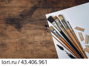 Художественные инструменты на старом темном деревянном столе. Набор кистей для масляной живописи, мастихины, белый холст. Стоковое фото, фотограф KOSIM / Фотобанк Лори