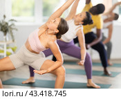 Girl stretching in Goddess Pose with side bend in yoga class. Стоковое фото, фотограф Яков Филимонов / Фотобанк Лори